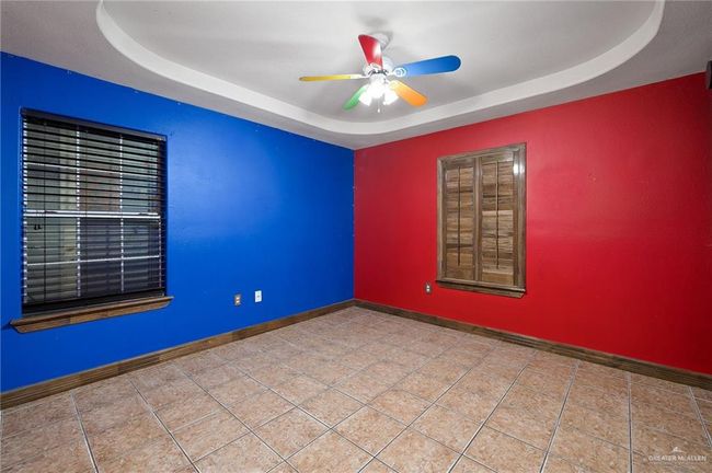 Tiled empty room featuring ceiling fan and a tray ceiling | Image 11