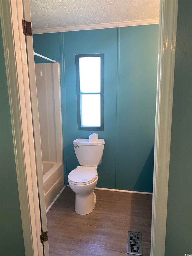 Full bath with crown molding, a textured ceiling, wood finished floors, and shower / washtub combination | Image 22