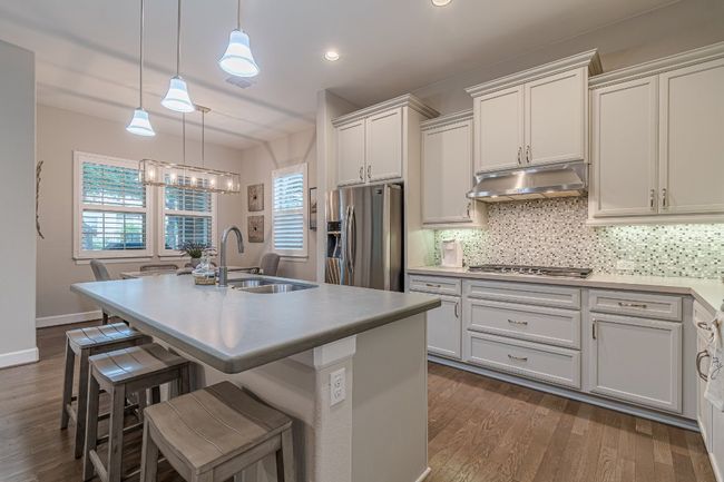 Kitchen featuring stainless steel appliances, a sink, under cabinet range hood, dark wood-style floors, and recessed lighting | Image 12
