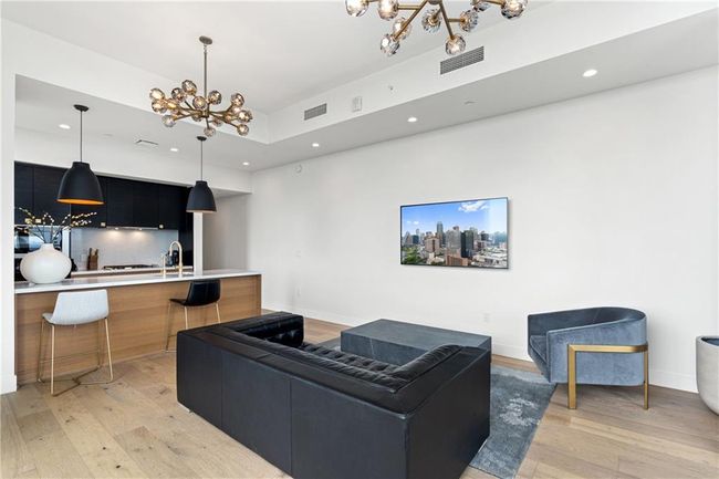 Living area with an inviting chandelier, light wood-style flooring, and visible vents | Image 5