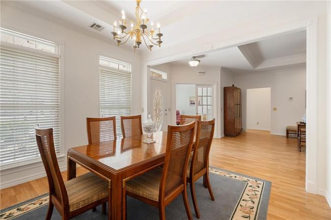 Dining room with light wood-style floors, visible vents, an inviting chandelier, and crown molding | Image 12