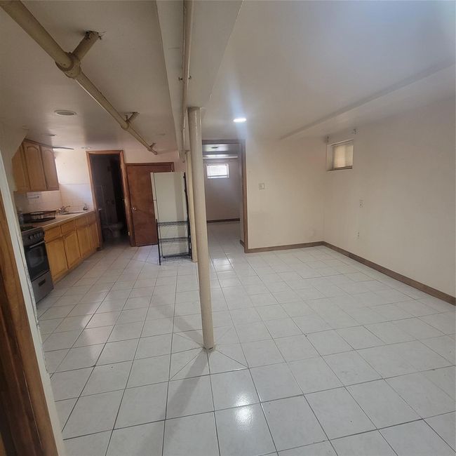 Below grade area with light tile patterned floors, a sink, and baseboards | Image 4