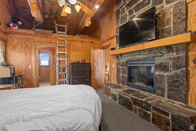 Bedroom featuring carpet, wood ceiling, ceiling fan, wooden walls, and beamed ceiling | Image 15