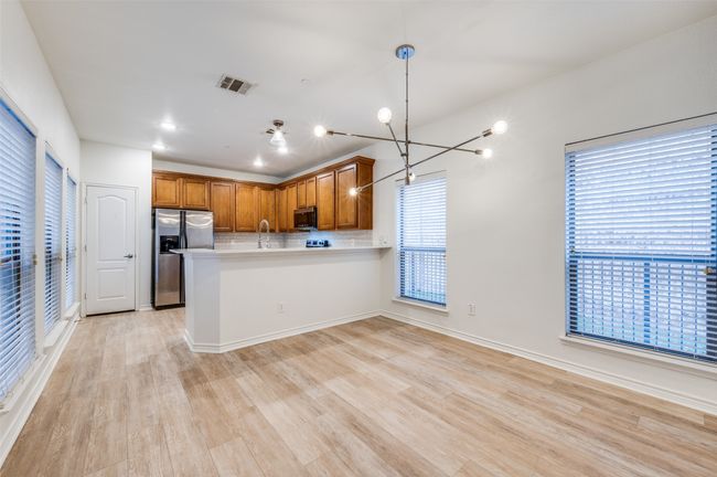 Kitchen featuring appliances with stainless steel finishes, light wood-style floors, light countertops, backsplash, and a peninsula | Image 9