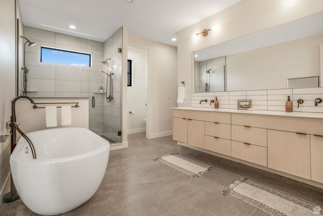 Full bath with concrete floors, a freestanding bath, a stall shower, double vanity, and backsplash | Image 26