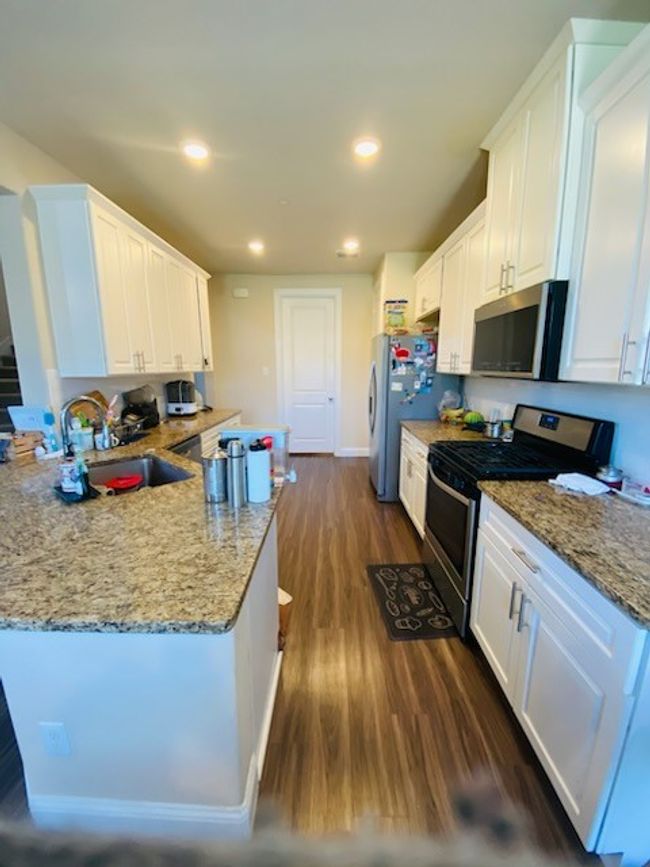 Kitchen featuring appliances with stainless steel finishes, white cabinetry, dark wood finished floors, a peninsula, and recessed lighting | Image 15