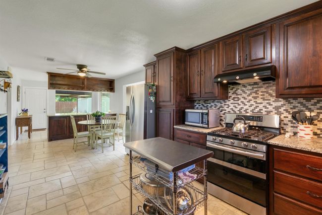 Kitchen leads into breakfast nook with huge window, another set of cabinets offers more storage and space to provide more seating. | Image 13