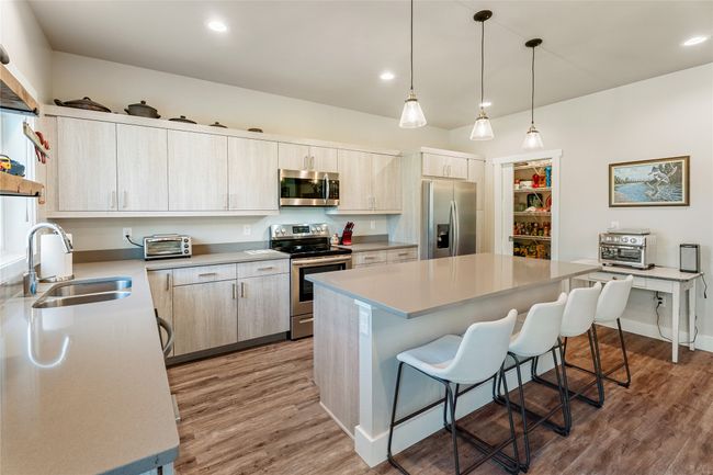 Kitchen with appliances with stainless steel finishes, a sink, a breakfast bar, light wood finished floors, and recessed lighting | Image 11