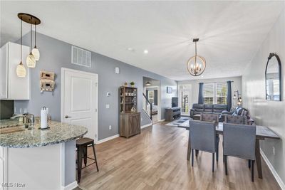 Dining room featuring a textured ceiling, a notable chandelier, sink, and light hardwood / wood-style flooring | Image 3