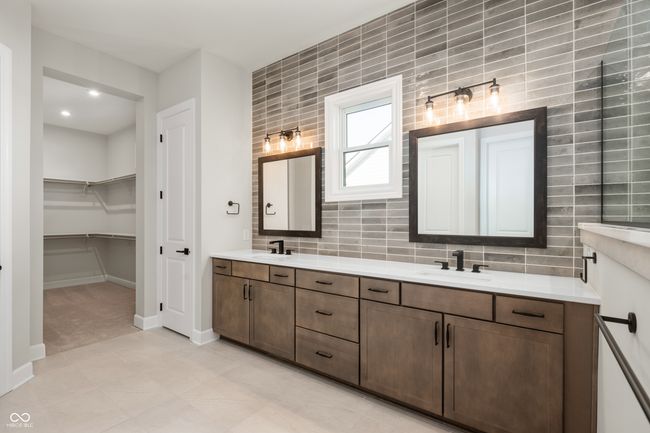 Primary bathroom rich in detail with decorative backsplash, beautiful cabinetry, double vanity, and large closet. | Image 18