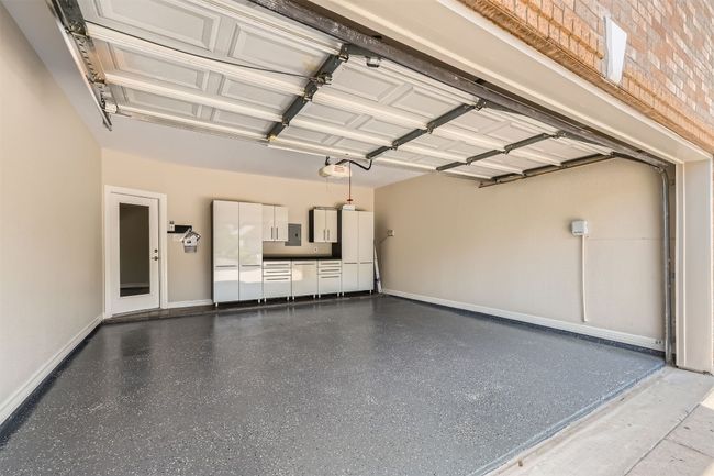 Garage featuring a garage door opener and baseboards | Image 38