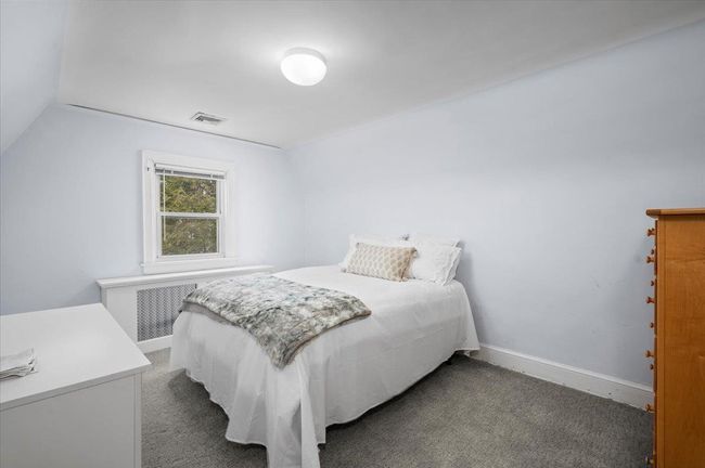 Carpeted bedroom featuring radiator, baseboards, lofted ceiling, and visible vents | Image 17