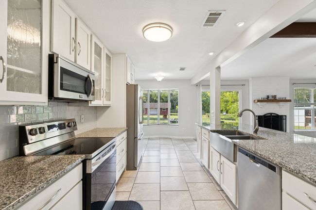 Kitchen featuring stainless steel appliances, backsplash, plenty of natural light, and white cabinets | Image 5