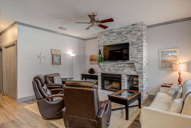 Living area with a ceiling fan, light wood-style flooring, a stone fireplace, and crown molding | Image 26