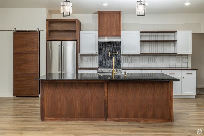 Kitchen featuring white cabinets, high end appliances, and a kitchen island with sink | Image 10