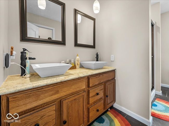 full bathroom featuring double vanity and a shower with door | Image 12