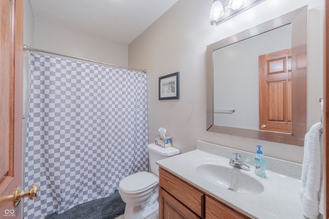 bathroom featuring a shower with shower curtain, toilet, and vanity | Image 29