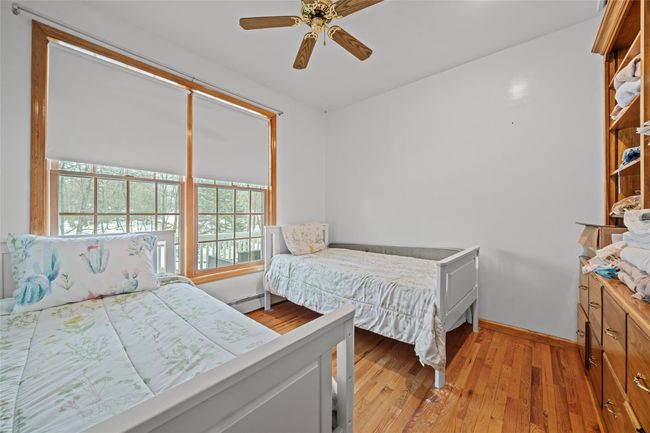 Bedroom featuring light wood finished floors, a ceiling fan, baseboards, and a baseboard radiator | Image 38