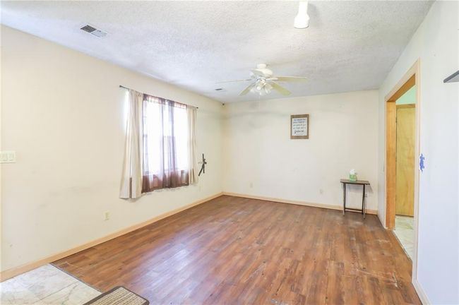 Unfurnished room with a textured ceiling, wood finished floors, ceiling fan, and baseboards | Image 8