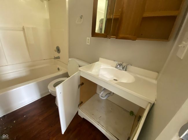 bathroom with wood finished floors, toilet, bathtub / shower combination, and a sink | Image 9