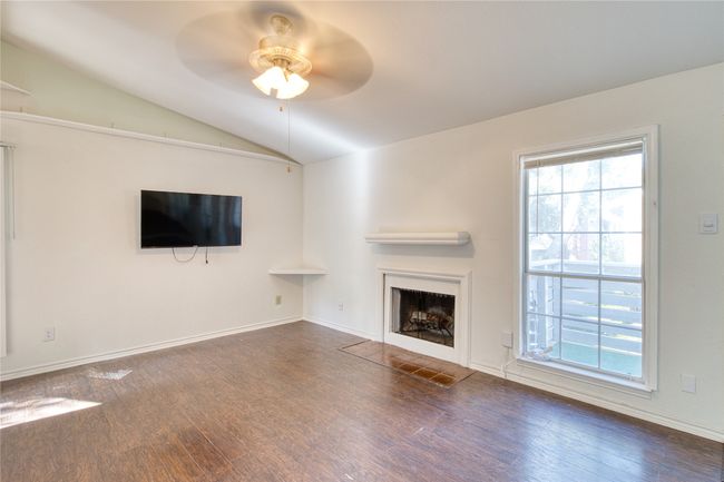 Unfurnished living room featuring vaulted ceiling, a ceiling fan, wood finished floors, and a fireplace with flush hearth | Image 10
