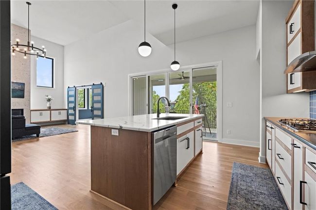 Kitchen with stainless steel appliances, exhaust hood, high vaulted ceiling, a chandelier, and healthy amount of natural light | Image 13