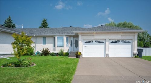 Ranch-style exterior with a dual garage featuring decorative window inserts, an asphalt shingle roof, and a concrete driveway | Card Image