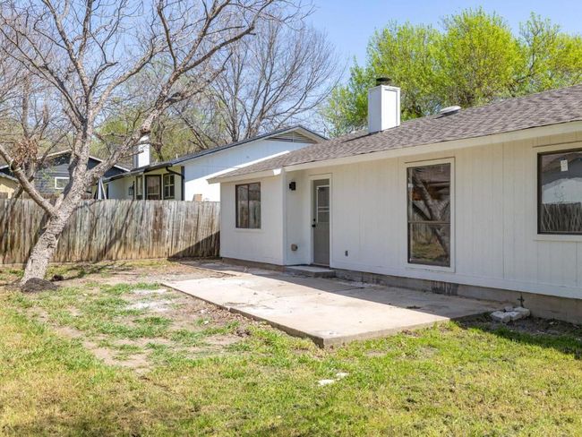 Rear view of house featuring a patio, fence, a yard, a chimney, and a shingled roof | Image 26