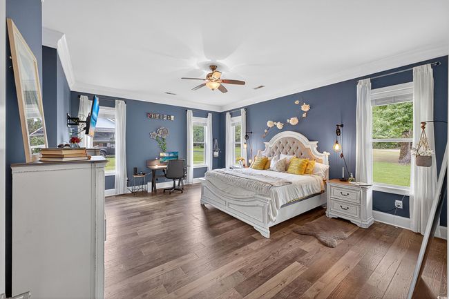 Bedroom featuring dark wood-style flooring, crown molding, and a ceiling fan | Image 18