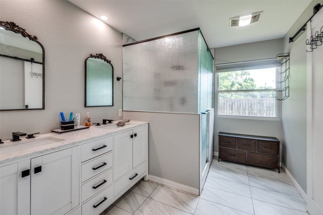 Bathroom with double vanity, a stall shower, and marble look tile flooring | Image 15