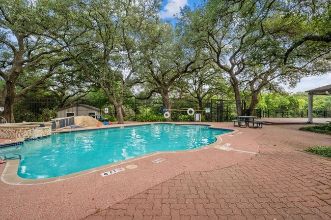 Community pool featuring a patio area and view of scattered trees | Image 12