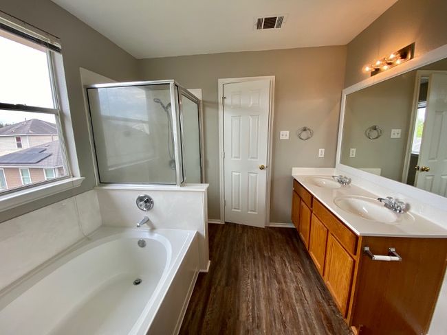 Full bathroom featuring a garden tub, double vanity, wood finished floors, and a shower with door | Image 23