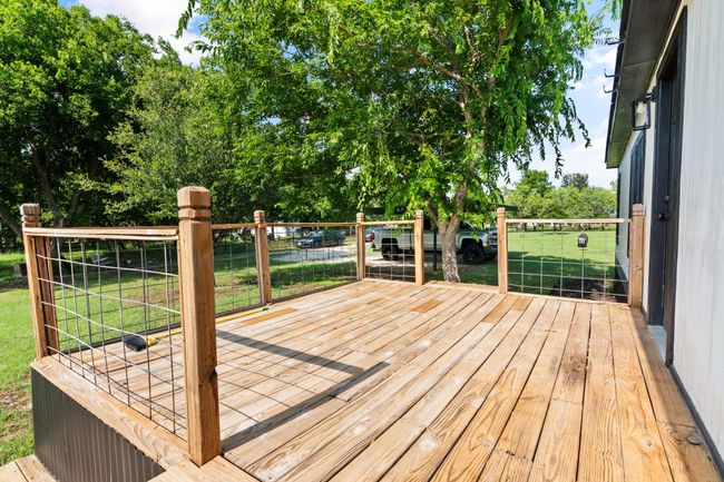 Wooden deck with a lawn and view of wooded area | Image 11