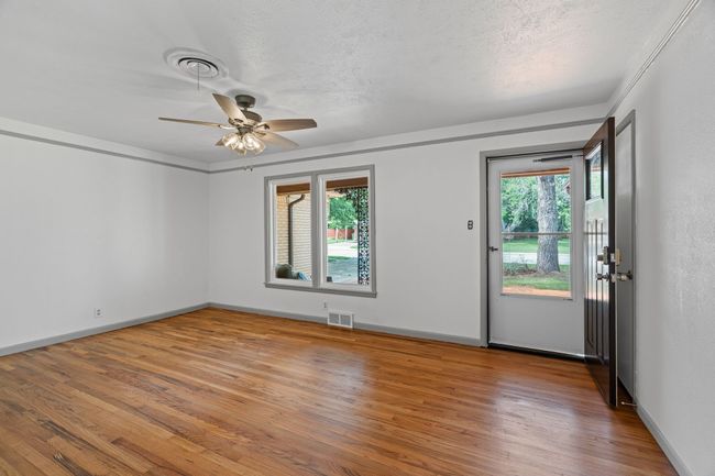 Living room with wood finished floors, ceiling fan, and a textured ceiling | Image 7