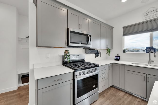 Kitchen with a sink, gray cabinets, light wood-style floors, and appliances with stainless steel finishes | Image 7