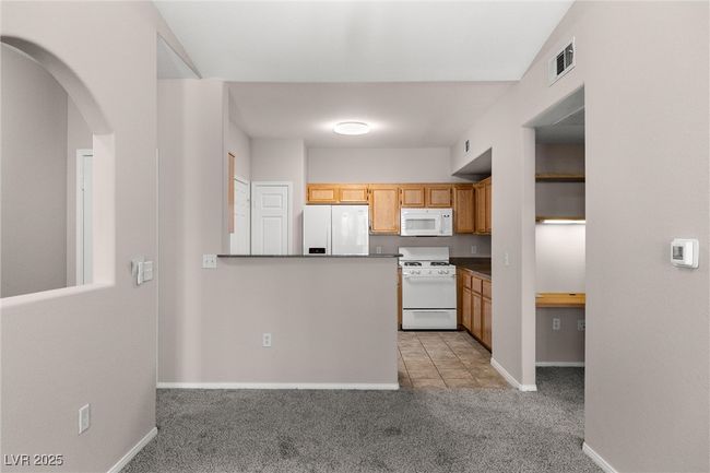 Kitchen with white appliances, visible vents, light carpet, baseboards, and arched walkways | Image 14