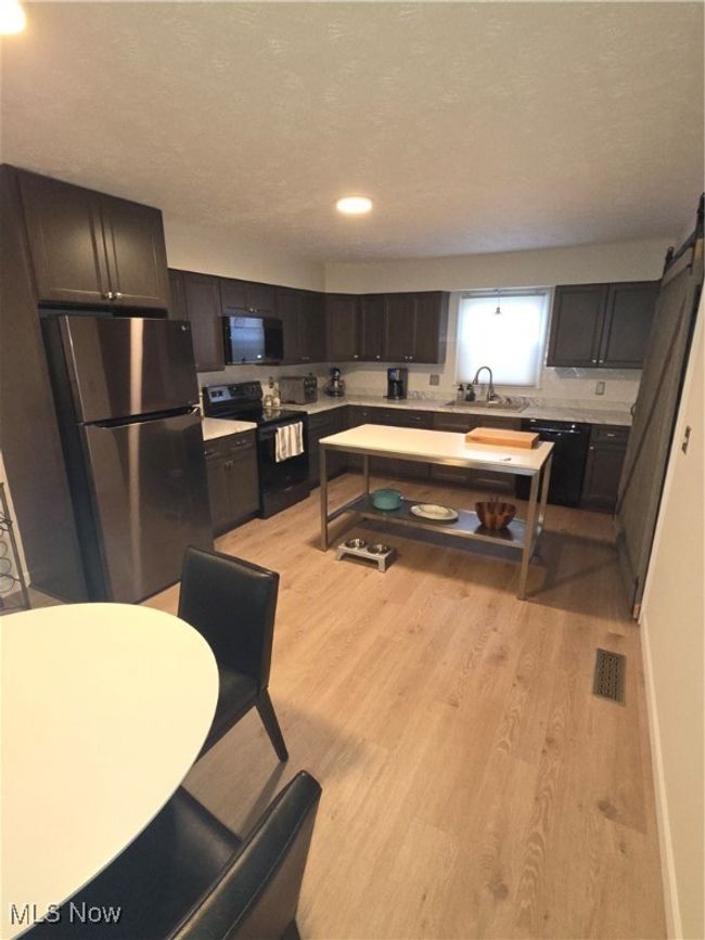 Kitchen featuring range, light countertops, light wood-style floors, fridge, and a sink | Image 7