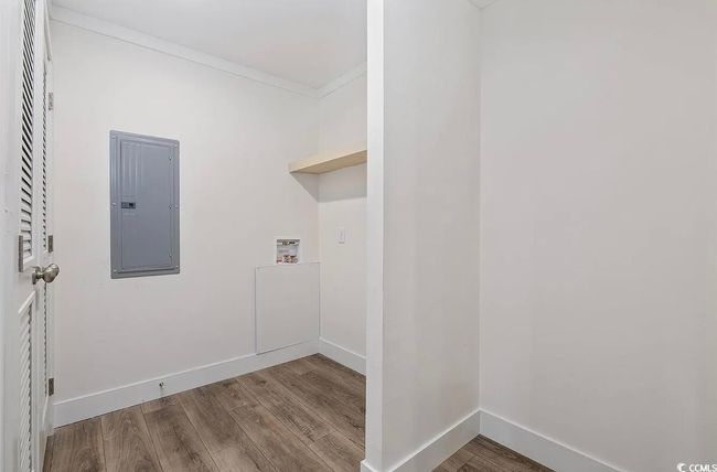 Laundry area with electric panel, wood finished floors, hookup for a washing machine, and ornamental molding | Image 9