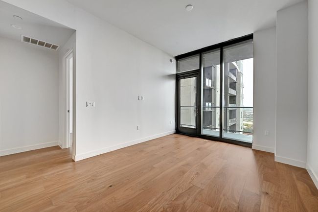 Unfurnished room featuring a wall of windows, baseboards, wood finished floors, and visible vents | Image 11