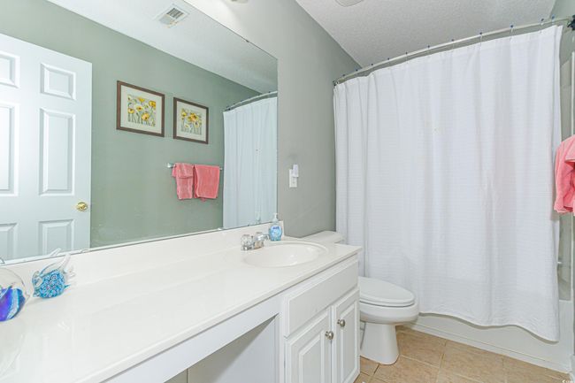 Full bathroom with toilet, a textured ceiling, vanity, shower / bath combo, and tile patterned flooring | Image 27