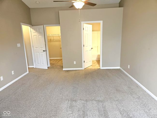 unfurnished bedroom featuring ensuite bathroom, a closet, baseboards, carpet, and a walk in closet | Image 29