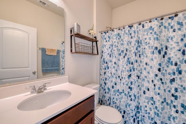 Full bathroom with visible vents, curtained shower, toilet, and vanity | Image 20