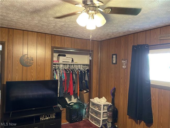 Bedroom featuring a closet, ceiling fan, and wooden walls | Image 13