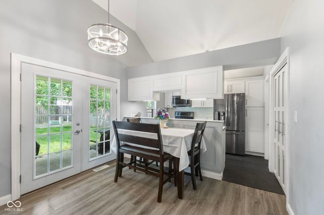dining area featuring french doors, dark wood-style floors, a chandelier, and high vaulted ceiling | Image 7