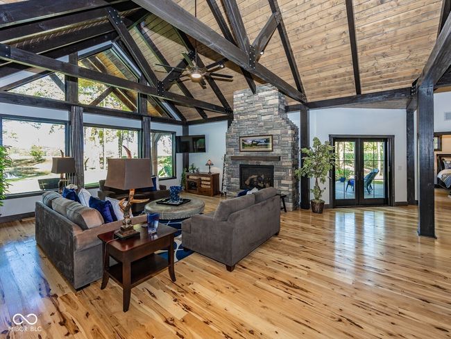 living room with high vaulted ceiling, a fireplace, light wood-type flooring, beam ceiling, and ceiling fan | Image 6