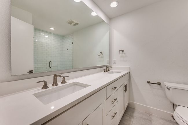 Bathroom featuring toilet, double vanity, a stall shower, baseboards, and recessed lighting | Image 23