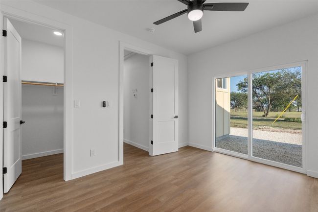 Secondary bedroom with a spacious closet, access to exterior, light wood-style flooring, and a ceiling fan | Image 7