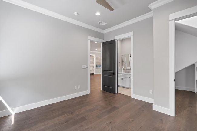 Guest bedroom on main level featuring dark wood-type flooring, visible vents, baseboards, and ornamental molding | Image 12