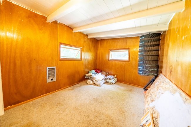 Carpeted spare room with plenty of natural light, beamed ceiling, wooden walls, and heating unit | Image 11
