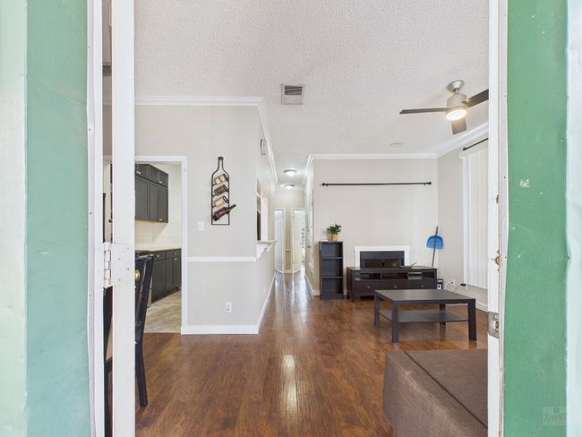Living room with ornamental molding, wood finished floors, a ceiling fan, and a textured ceiling | Image 5